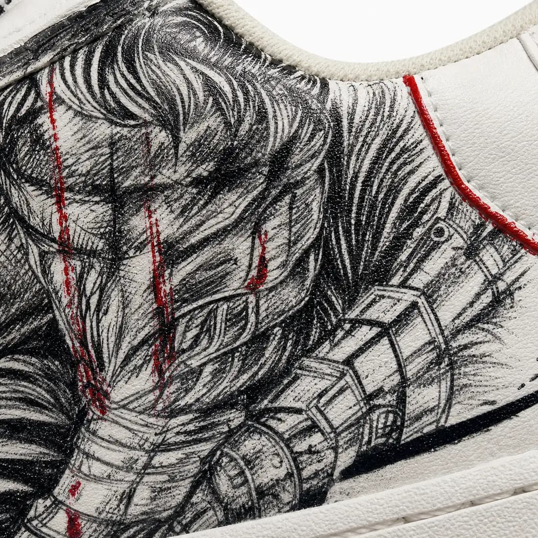 Macro detail: hand-inked linework and red paint across white leather
