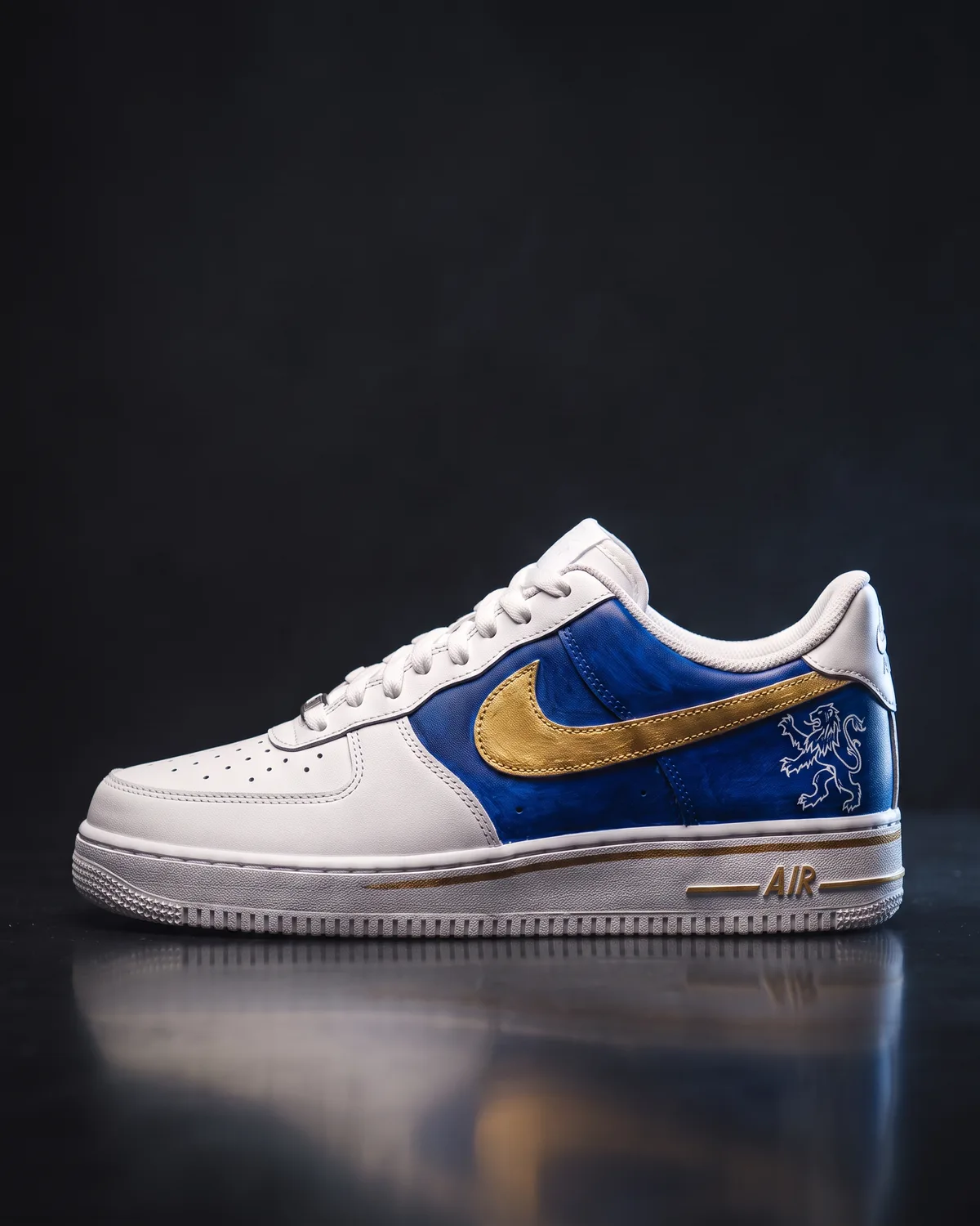 A white Air Force 1 with a royal blue quarter panel laid in layered brushwork, a hand-painted gold swoosh and a white heraldic lion